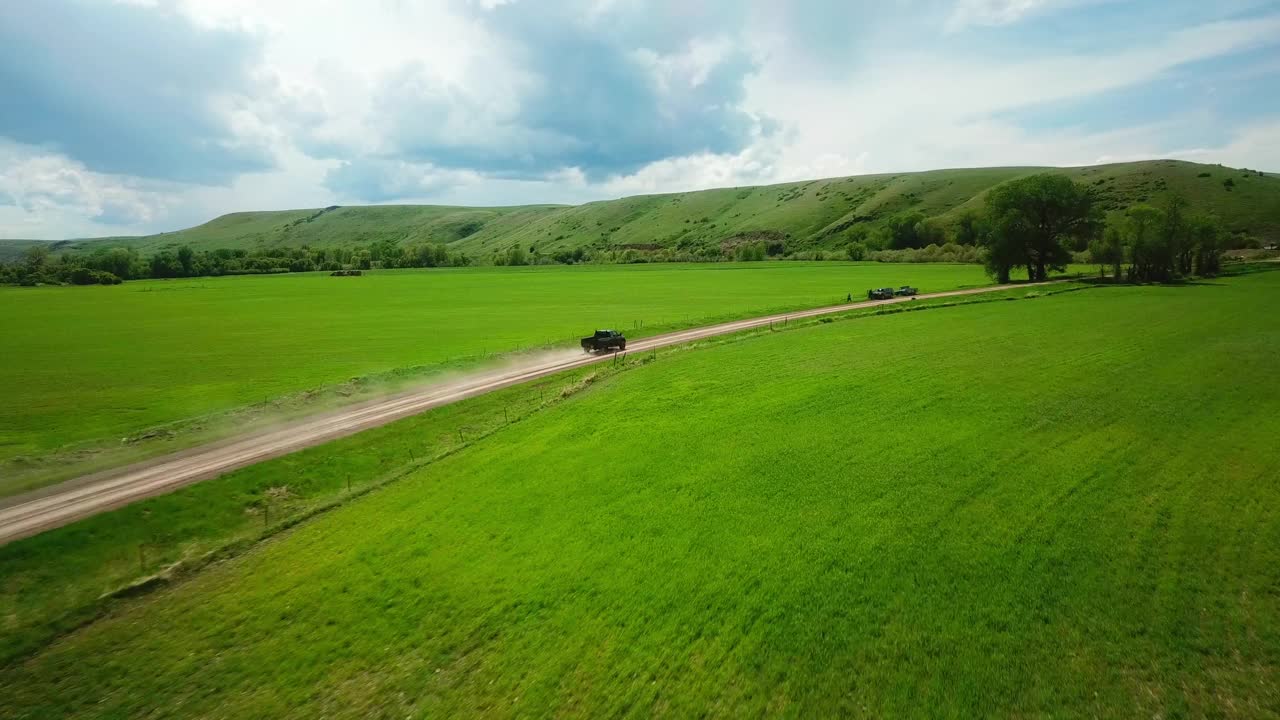 空中平移拍摄的皮卡车在泥泞的道路上移动的田野对天空-比林斯，蒙大拿州视频素材