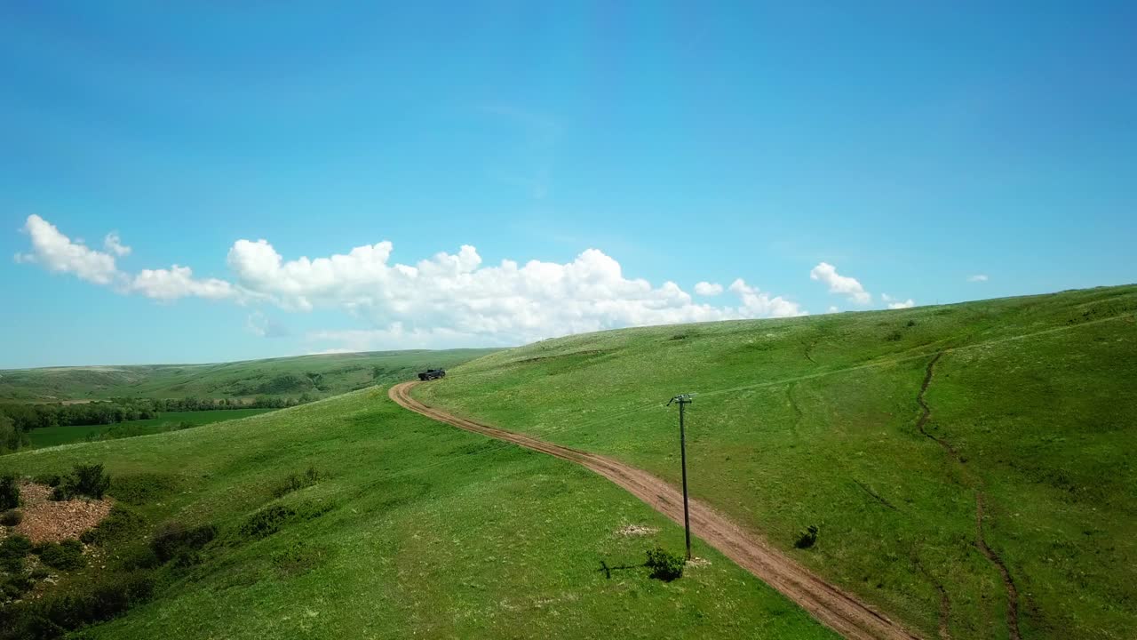 空中拍摄的皮卡车在绿山上移动，无人机飞越景观对天空-比林斯，蒙大拿州视频素材