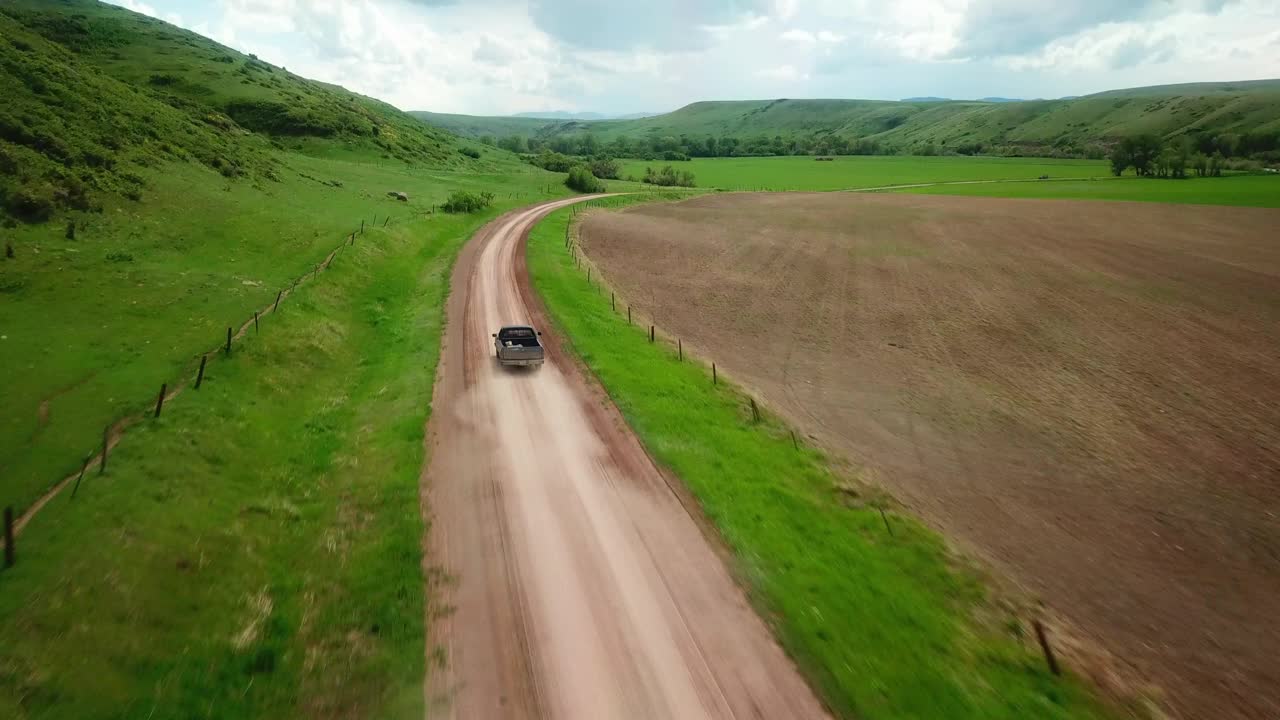 空中向前拍摄的皮卡车移动在泥泞的道路在绿色的田野对天空-比林斯，蒙大拿州视频素材