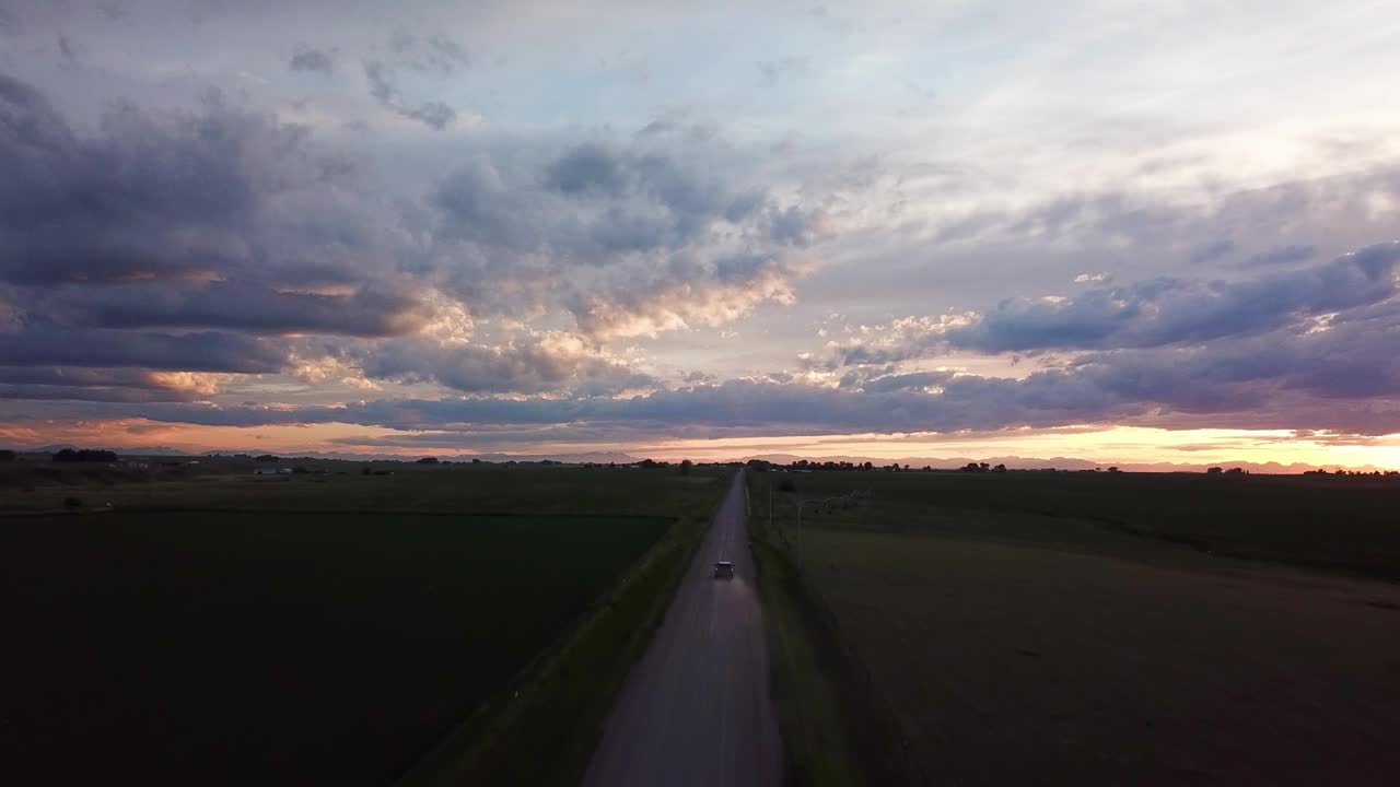 空中向前拍摄的车辆行驶在乡村道路对多云的天空在日落-比林斯，蒙大拿州视频素材