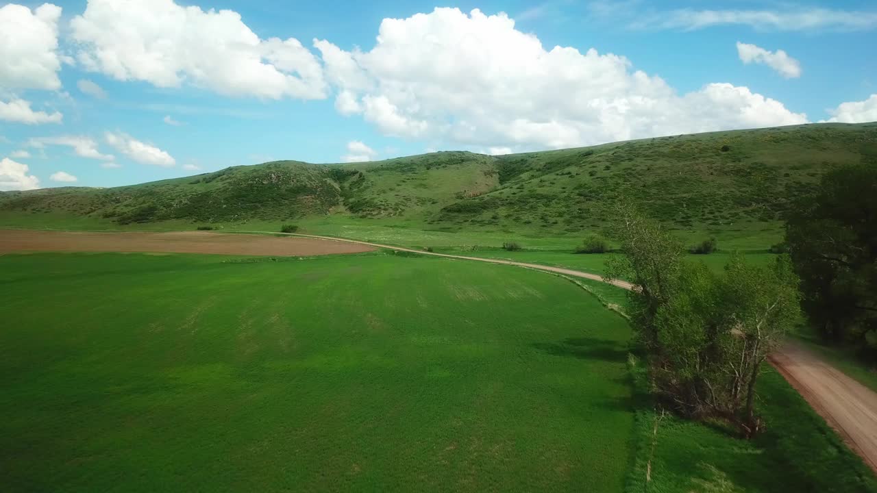 空中下降拍摄的皮卡车在乡村道路上移动，无人机飞行在绿色的田野对天空-比林斯，蒙大拿州视频素材