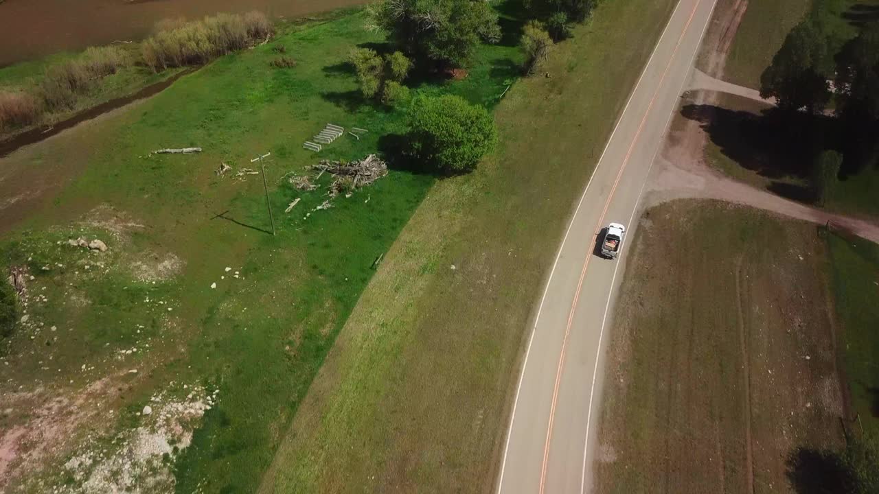 空中拍摄的皮卡在乡村道路上移动，无人机在田野上向后移动-比林斯，蒙大拿州视频素材