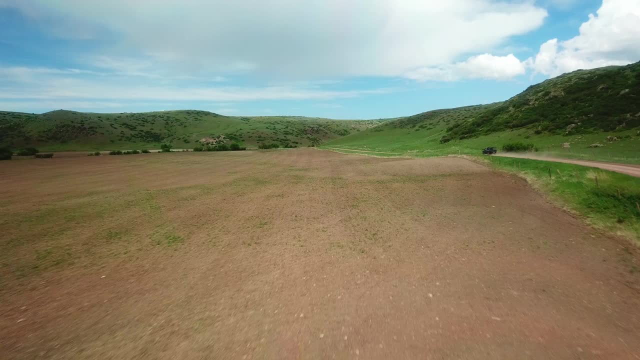 空中拍摄的皮卡车在泥泞的道路上移动在田野中，无人机飞行在景观对天空-比林斯，蒙大拿州视频素材