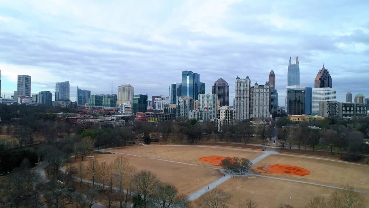 空中拍摄的地面在光秃秃的树木附近的现代建筑，无人机上升在城市对多云的天空-亚特兰大，乔治亚州视频素材