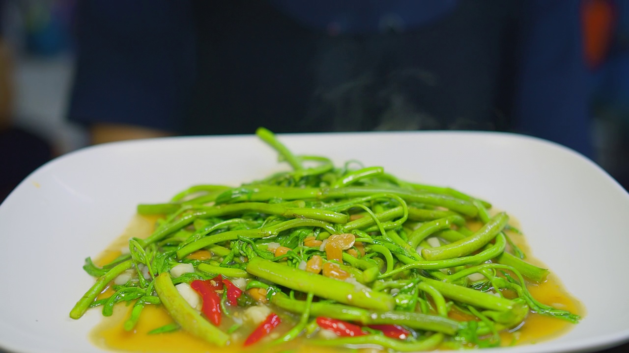 近距离烹饪美味健康的蔬菜炒新鲜的绿色辣水含羞草在厨房，泰国菜视频素材