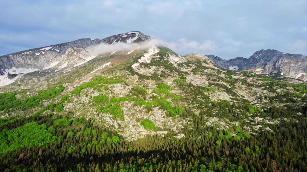 飞越山峰，到达山脚下被森林环绕的湖泊视频素材