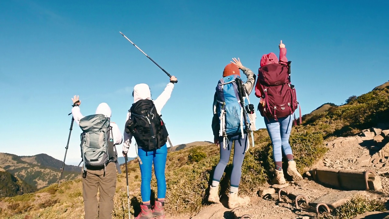 在山顶上高举双臂的徒步旅行者背对着群山。视频素材