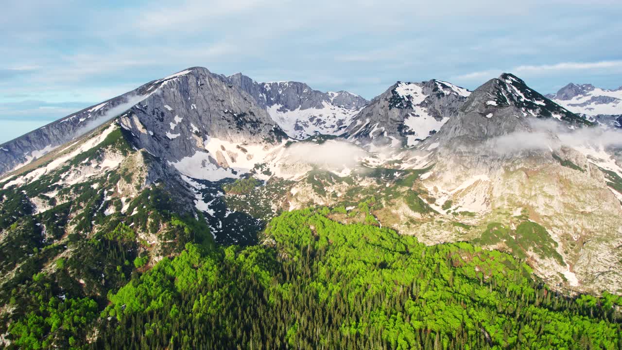 飞越山峰，到达山脚下被森林环绕的湖泊视频素材