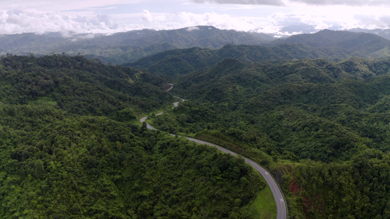 在森林景观之间的弯曲道路上的无人机视图视频素材