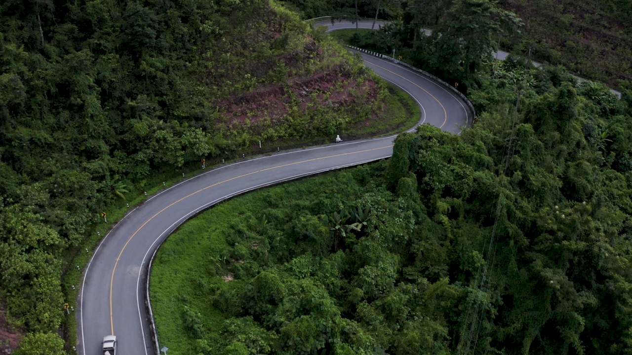 在森林景观之间的弯曲道路上的无人机视图视频素材