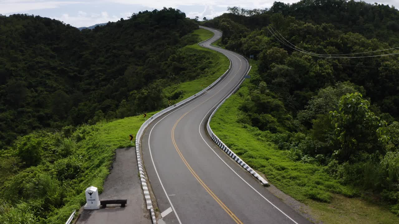 在森林景观之间的弯曲道路上的无人机视图视频素材