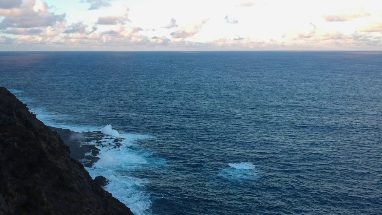 在日落时分，夏威夷瓦胡岛的海岸悬崖上，海浪拍打着靠近海岸线的岩石视频素材