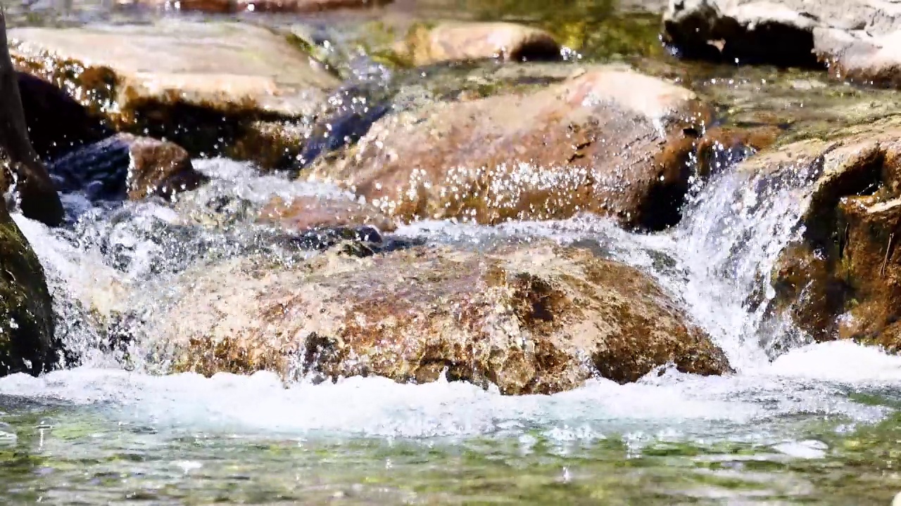 近距离拍摄了一股强大的水流过石头，山间河流。视频素材