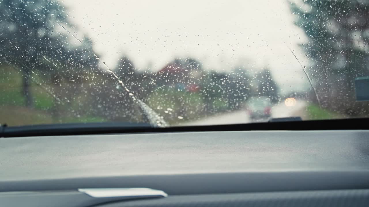 透过雨道上的挡风玻璃望去，雨刷正在运转。视频素材