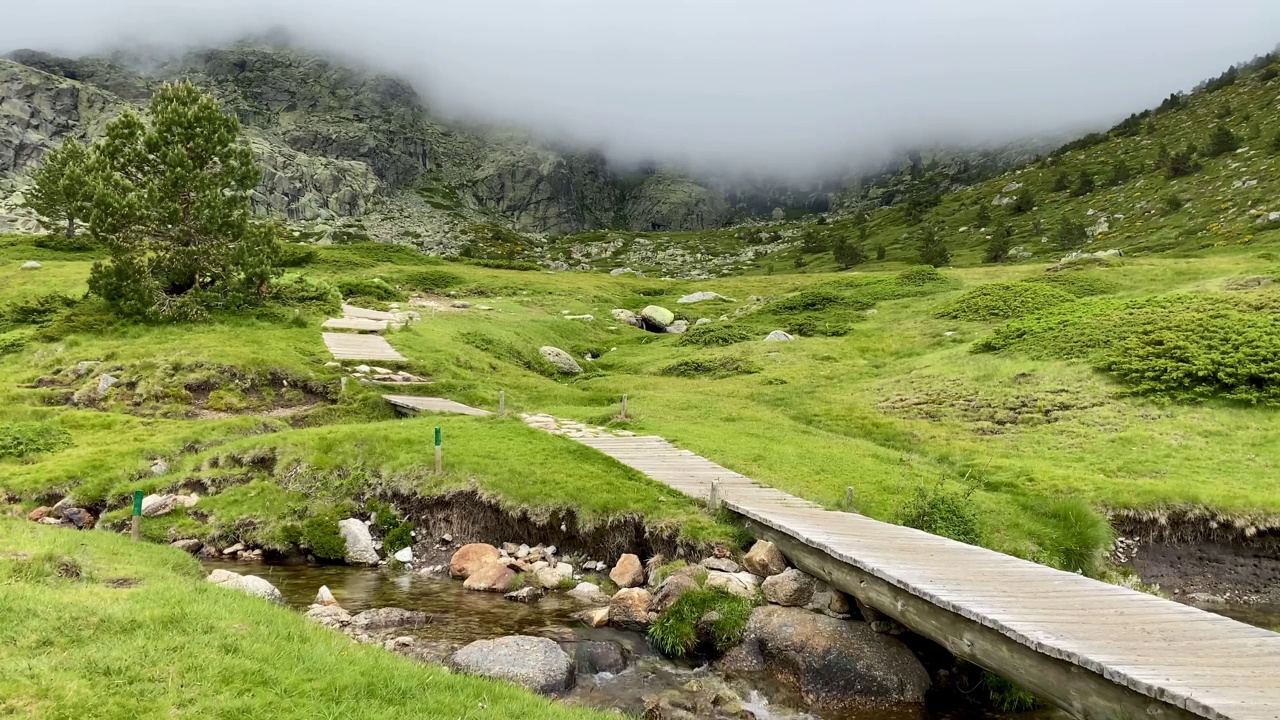 在阴天穿红色大衣的徒步旅行者在山里徒步旅行视频素材