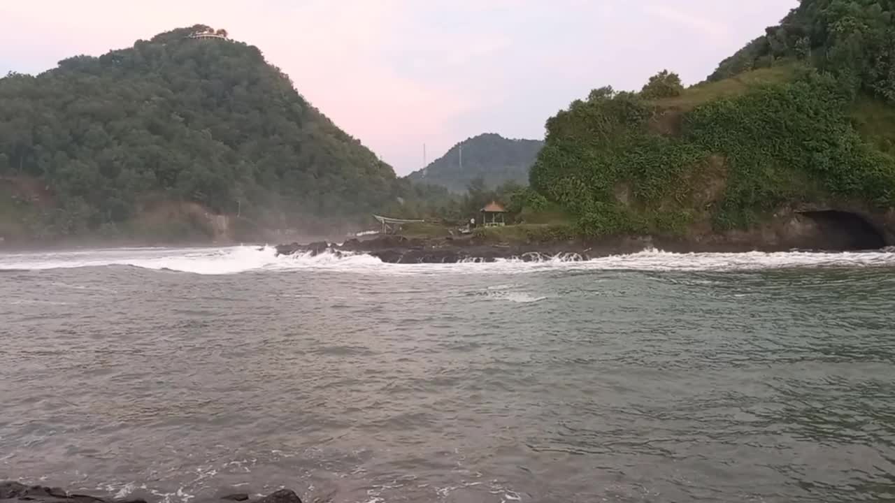 河口和海浪全景，以黑色山丘为背景。视频下载