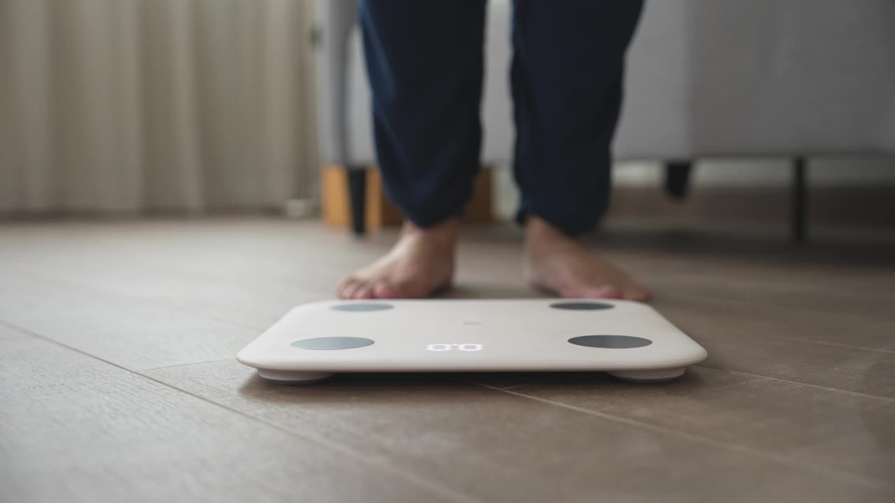 节食的女人站在体重秤上测量体重视频素材