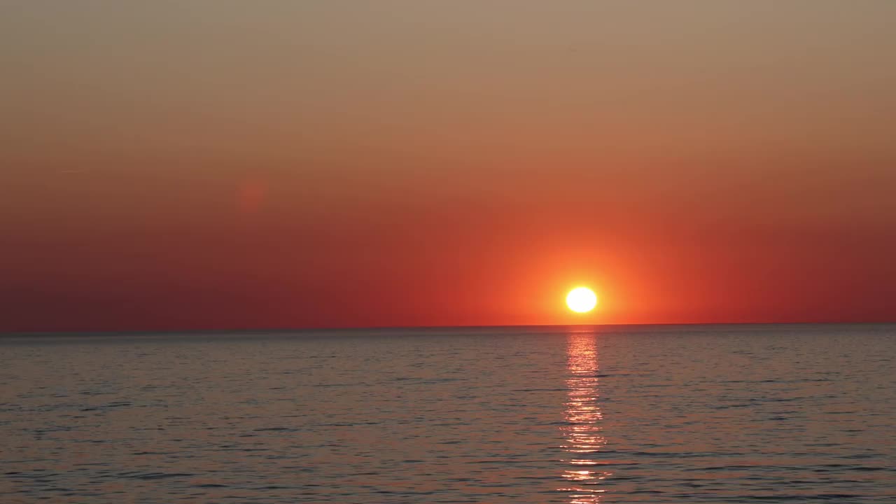 橘黄色的大太阳落在平静的海面上。视频素材