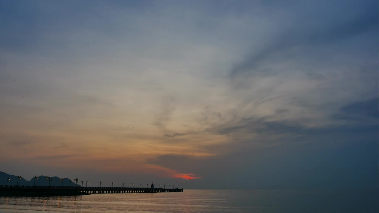 延时日出或日落，海面上漂浮的渔船，云景热带天气，彩色天空和地平线上的山脉轮廓视频素材