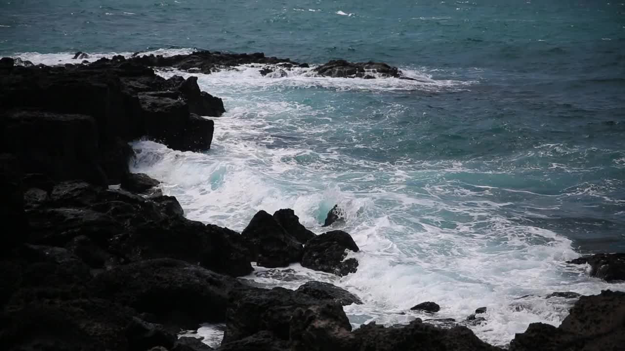 在济州岛海岸，白色的海浪冲击着黑色的玄武岩视频下载