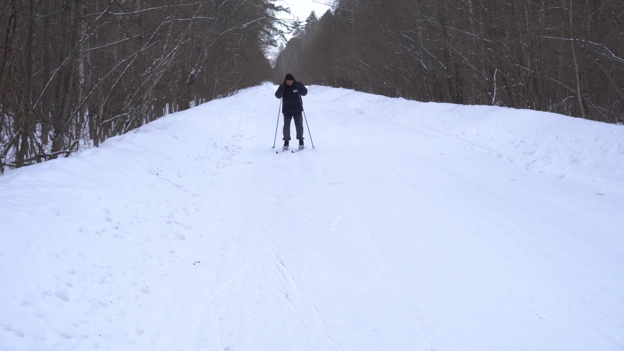 一个50岁的男人冬天在森林里滑雪视频素材