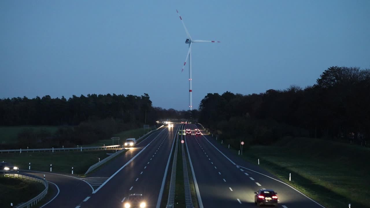 视频:蓝色时段乡村道路上的风力涡轮机和交通视频素材