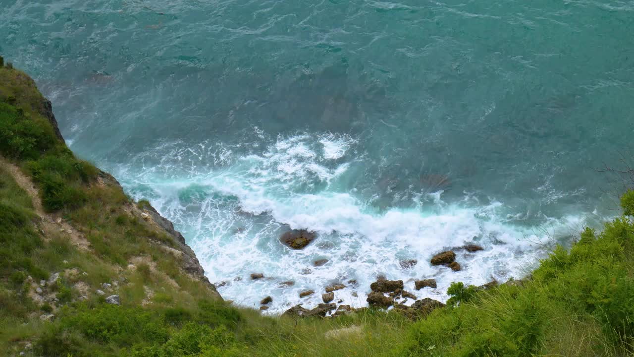 从上面看，海浪撞击着岩石。视频素材