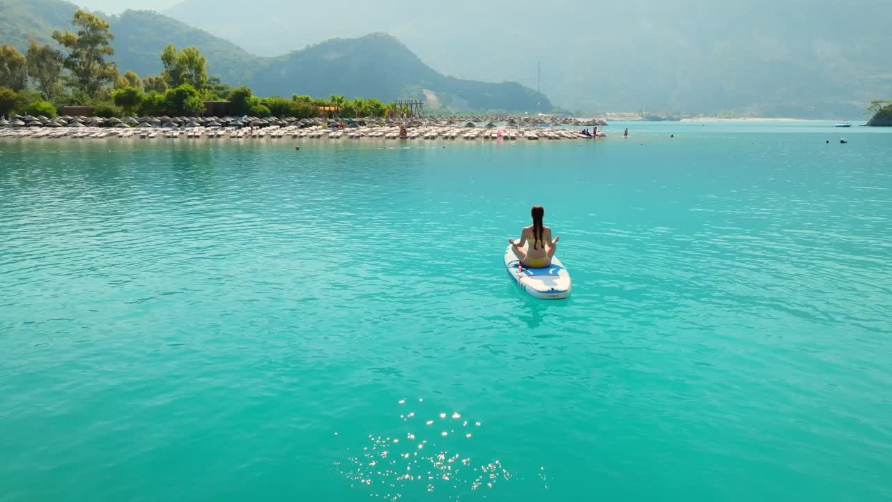 女子在海上练习立式桨板瑜伽。视频素材