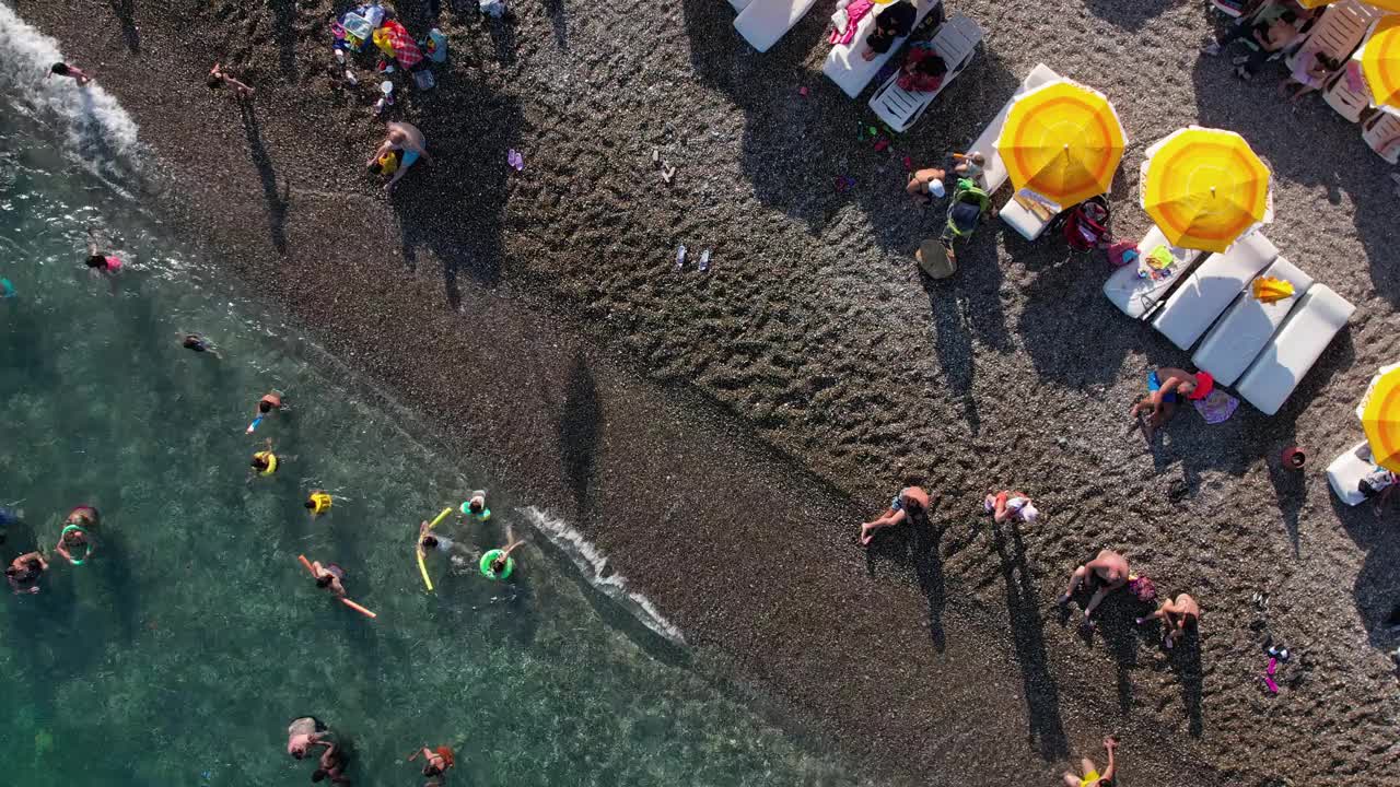 鸟瞰土耳其安塔利亚的konyaaltai海滩。一群人在海里游泳，在海滩上晒日光浴视频素材