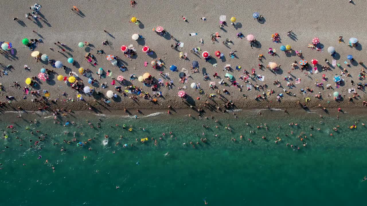 鸟瞰土耳其安塔利亚的konyaaltai海滩。一群人在海里游泳，在海滩上晒日光浴视频素材