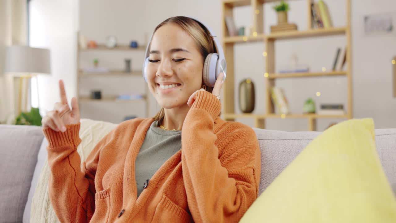 耳机，在家和快乐的女人听音乐，心理健康，青年电台和流媒体在沙发上。年轻的亚洲人或放松与音频技术在客厅，沙发或公寓的Kpop视频素材