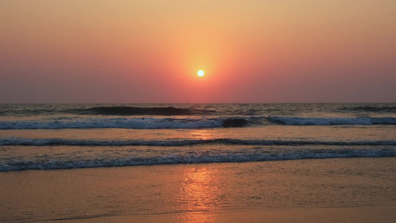 海洋上美丽的日落。在落日余晖的映衬下，白沫滚滚的海浪向海岸袭来。傍晚的天空笼罩着一层粉红色的薄雾。4 k。视频素材