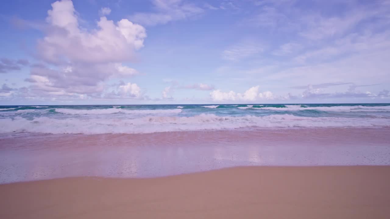 在阳光明媚的日子里，海浪冲击着沙滩，夏日沙滩背景视频素材