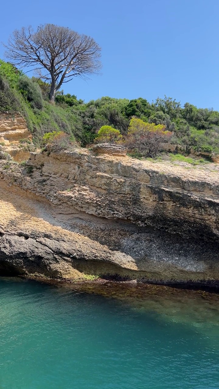 清澈的大海碧蓝的海水和岩石海岸，垂直视频。视频素材