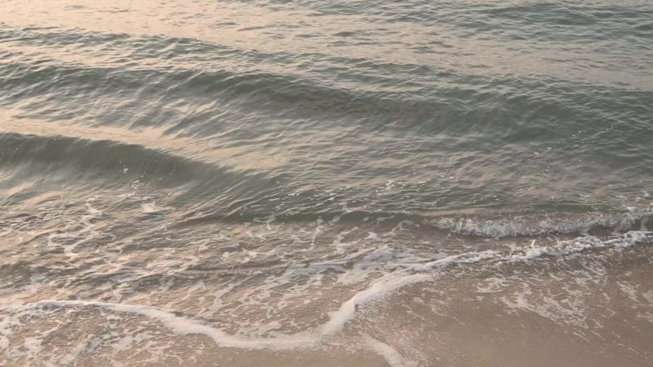 在日出或日落的热带海滩上，波浪飞溅。视频素材