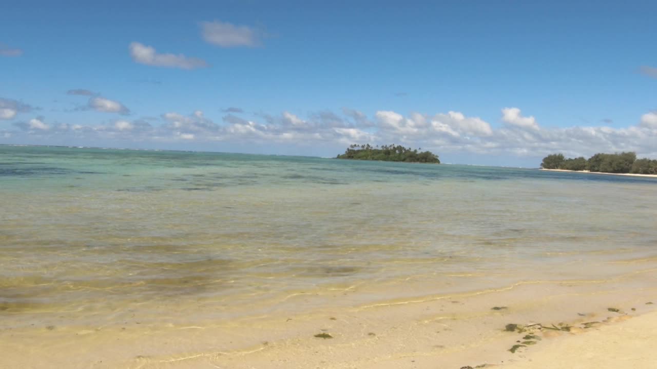 手握静止的视图看向高冈岛泻湖地平线从Muri海滩碧蓝清澈的海水在阳光明媚的蓝天晴朗的天气在拉罗汤加库克岛太平洋视频素材