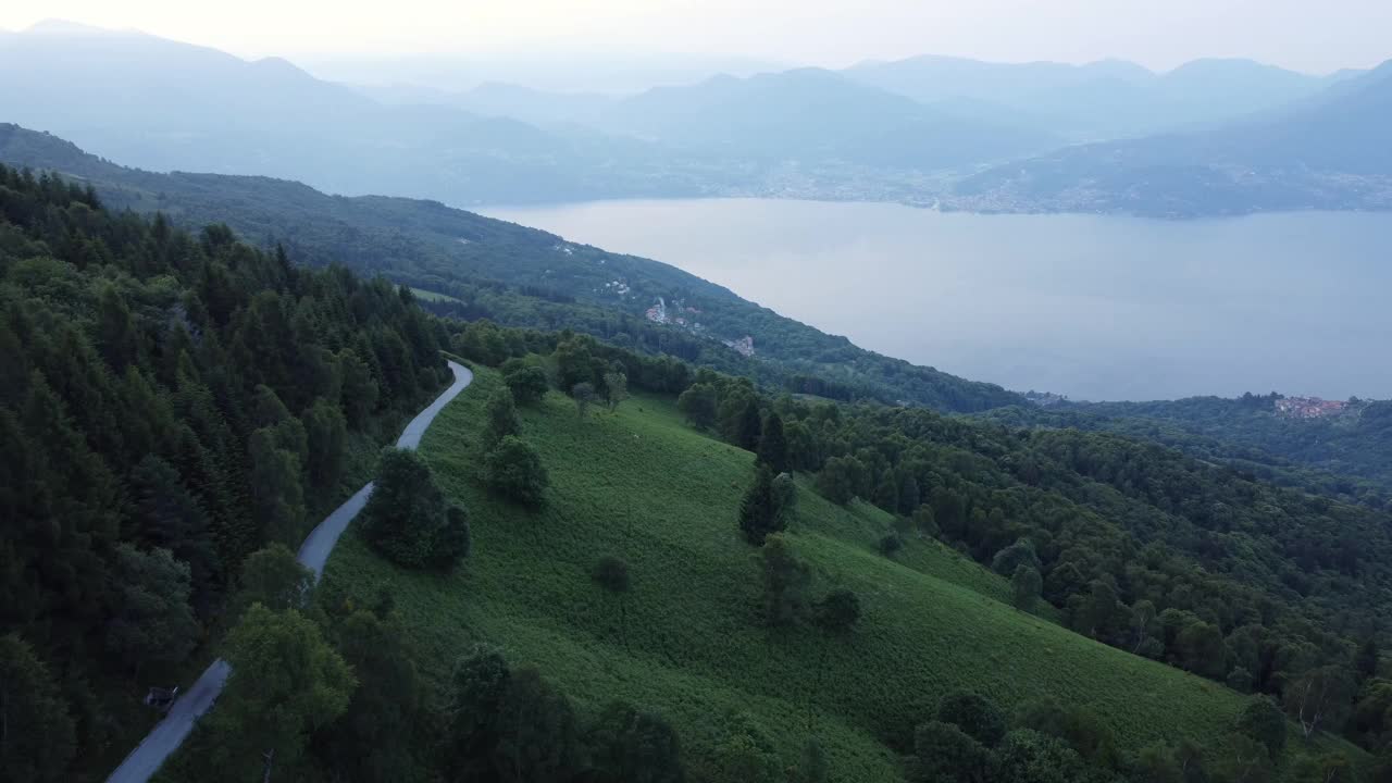 无人机拍摄的灰色天空下的绿色景观，有森林覆盖的山丘和湖泊视频素材