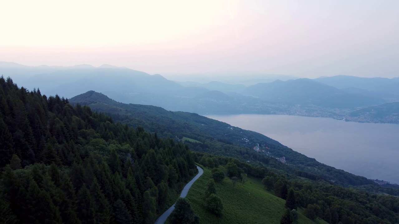 空中景观的绿色山脉和公路湖边与雾蒙蒙的天空在日落视频素材