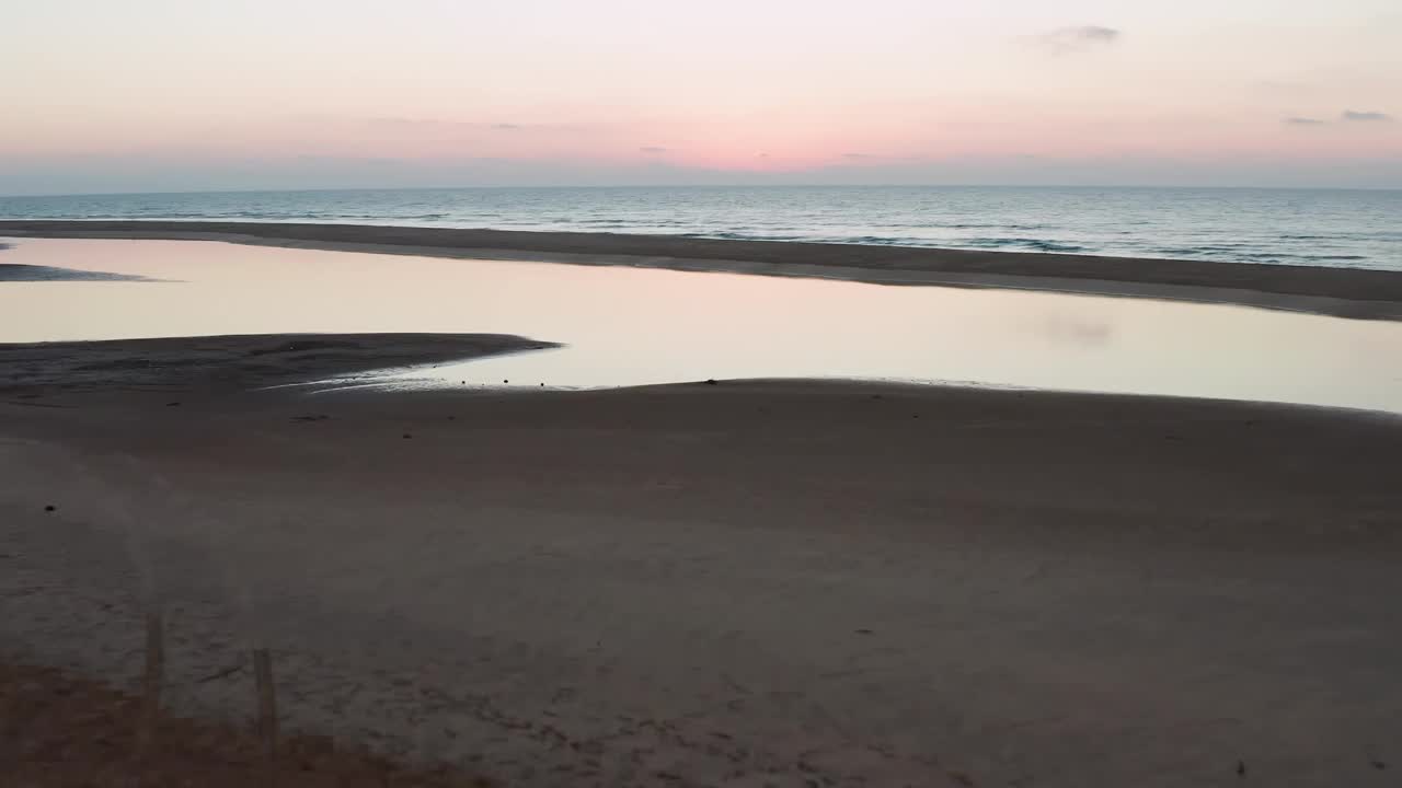 景观鸟瞰图的海滩与飞溅的水和橙色的夕阳天空在地平线上视频素材