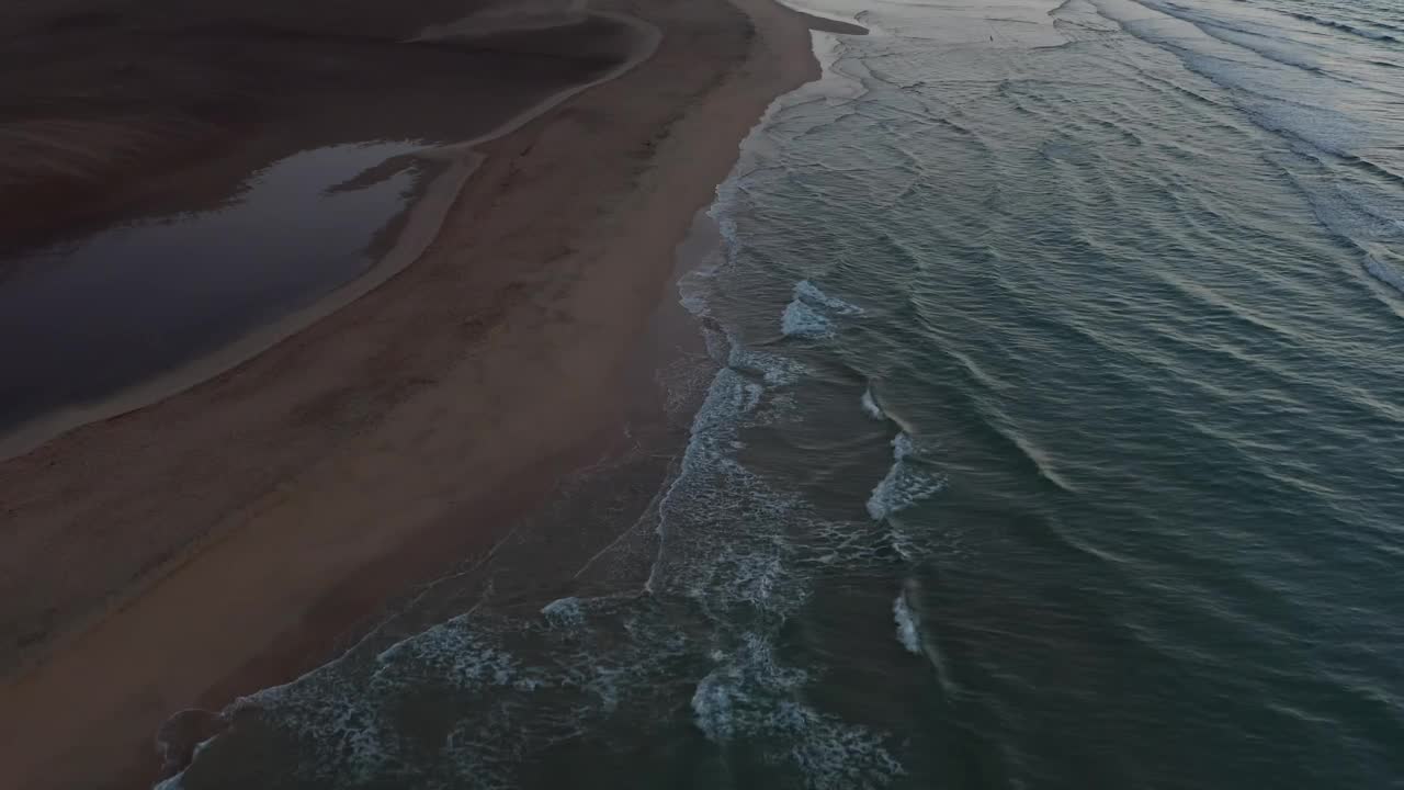 景观鸟瞰图的海滩与飞溅的水和日落的天空在地平线上视频素材