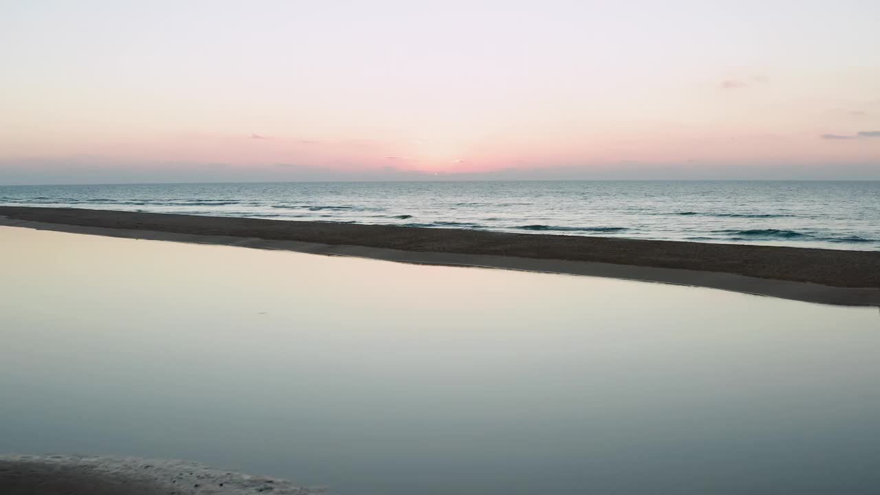 无人机镜头在海滩上移动到大海，夕阳和橙色的天空视频素材