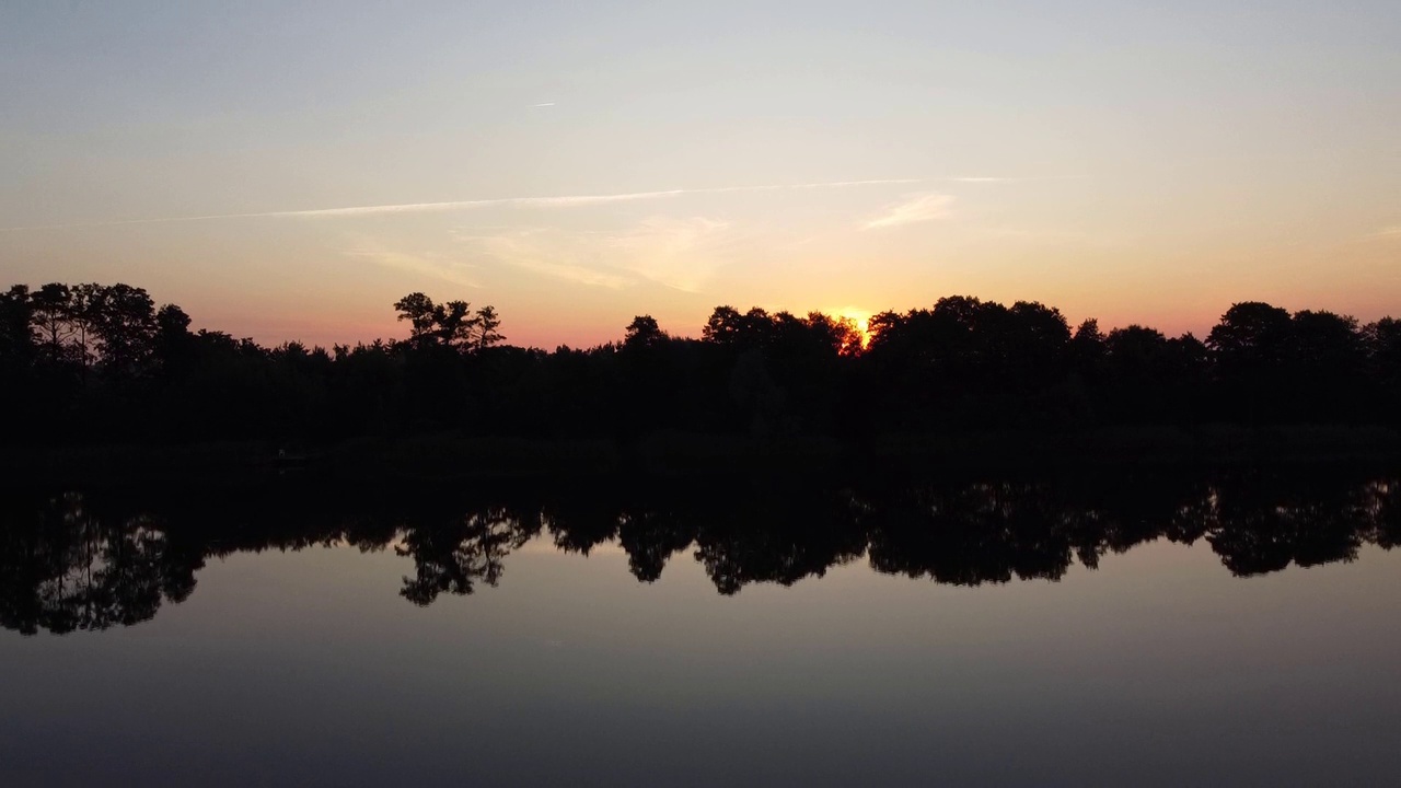 湖上的夕阳。太阳从森林里的湖面上升起。背景是麦田。一天的开始。视频下载