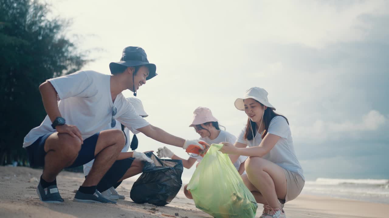 一群亚洲人用装满垃圾的塑料袋清理海滩。有环保和志愿观念的人。视频素材