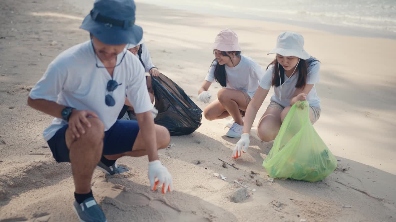 一群亚洲人用装满垃圾的塑料袋清理海滩。有环保和志愿观念的人。视频下载