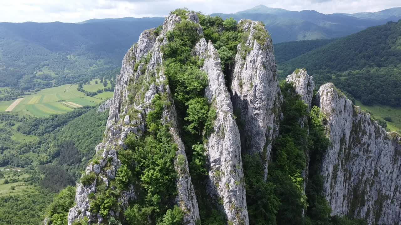 航拍视频，高高的岩石山脉覆盖着绿色的森林视频素材