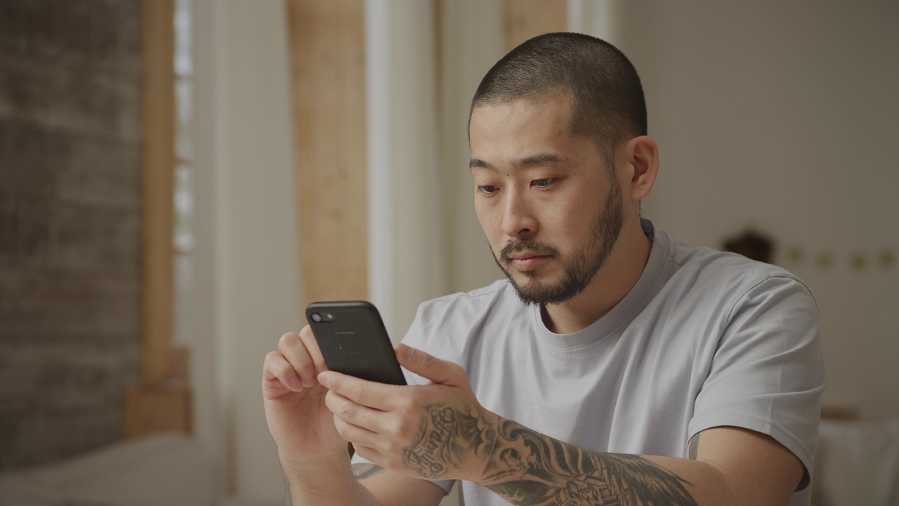 20多岁的亚洲男人用各种各样的面部表情刷智能手机视频素材