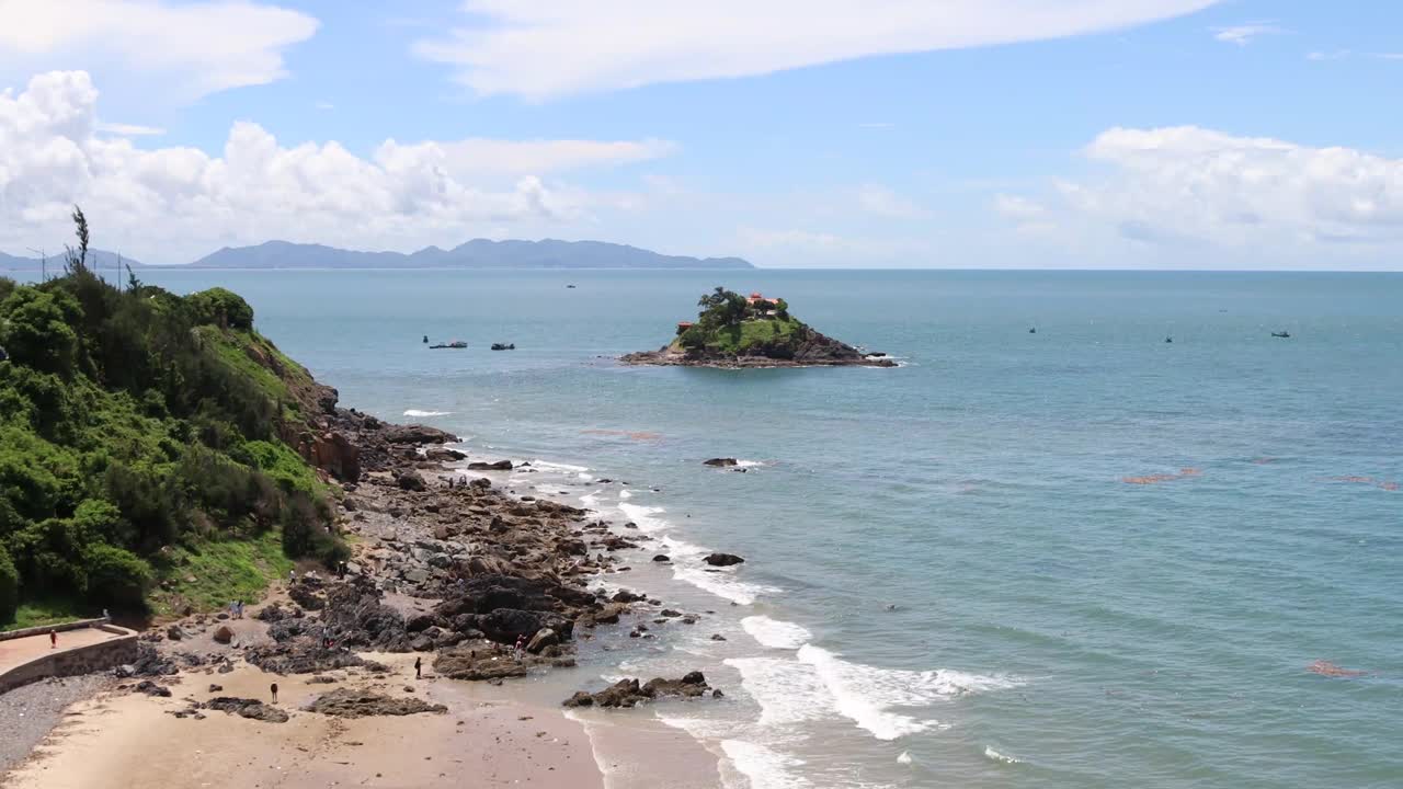 云头海滩的海岸线有蓝色的海洋。海浪涌来，游客们沿着海滩放松。视频下载