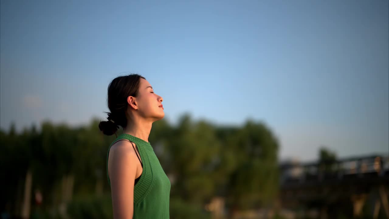 年轻的亚洲女商人穿着绿色的衣服，被绿色的植物包围着，在一个城市的办公园区里沉思。生态户外。可持续的生活方式理念。视频素材