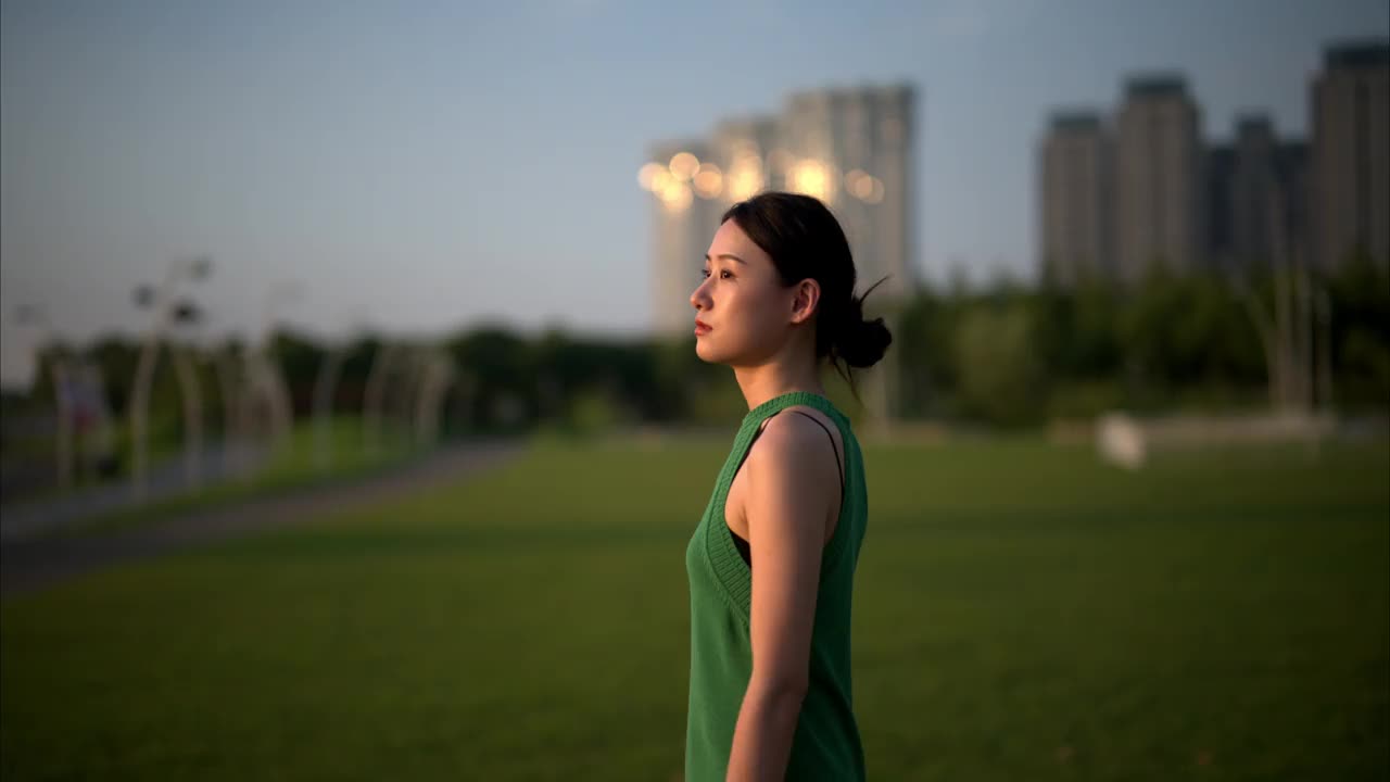 年轻的亚洲女商人穿着绿色的衣服，被绿色的植物包围着，在一个城市的办公园区里沉思。生态户外。可持续的生活方式理念。视频下载