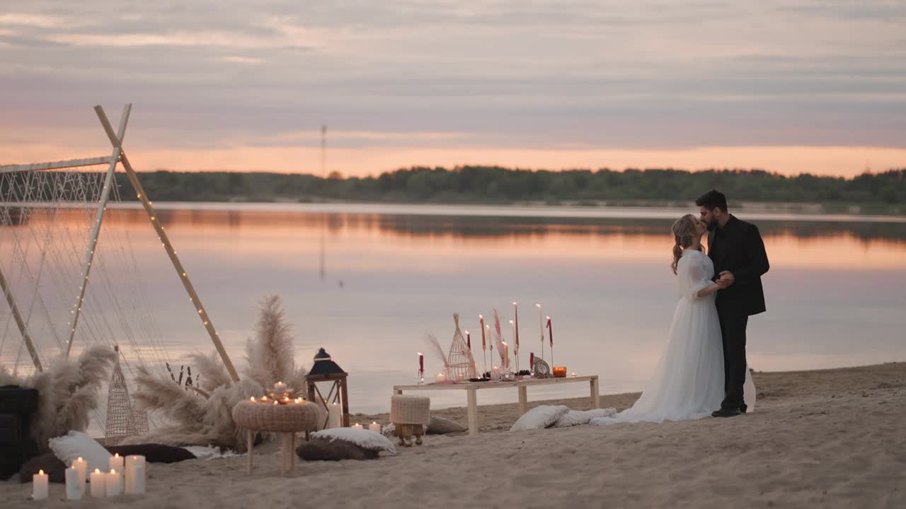 夕阳下，湖边浪漫的婚礼上，新婚夫妇温柔的拥抱和亲吻视频素材